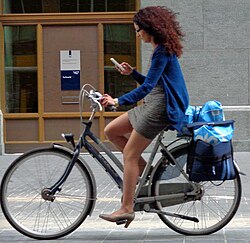 woman riding a bike while looking at her phone